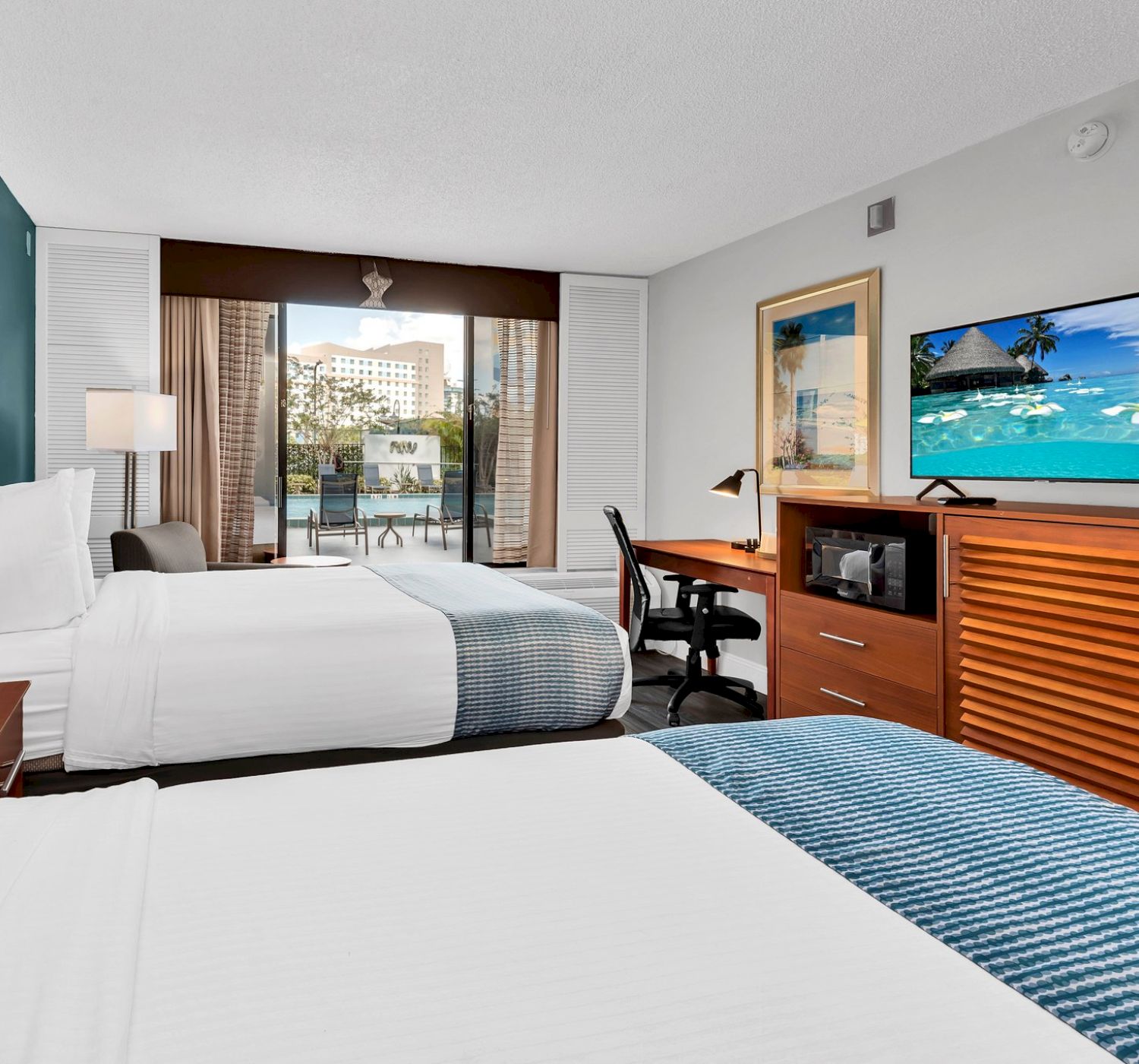 The image shows a hotel room with two beds, a TV, a desk, and a window overlooking a cityscape.