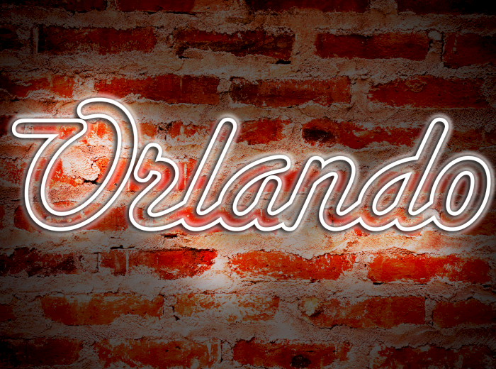 A neon sign spelling "Orlando" is mounted on a brick wall background, illuminated with a bright glow.